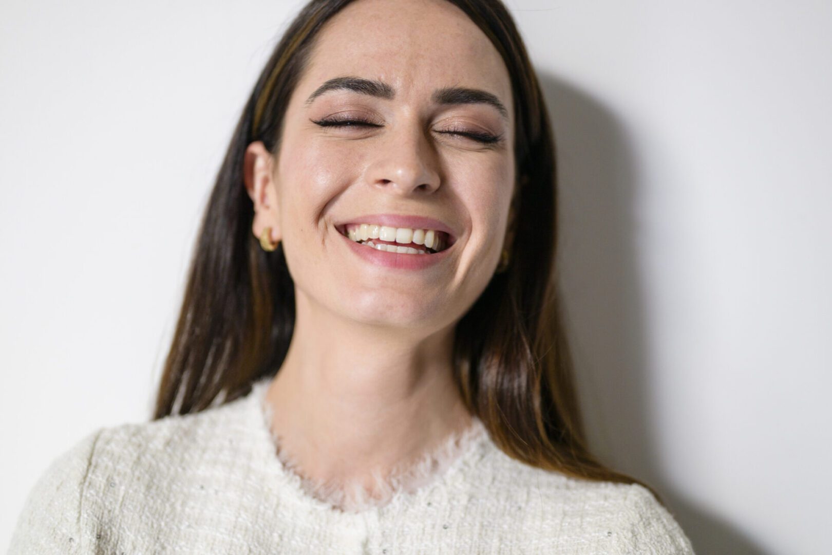 Portrait of an elegant and  cheerful businesswoman smiling with closed eyes and white background