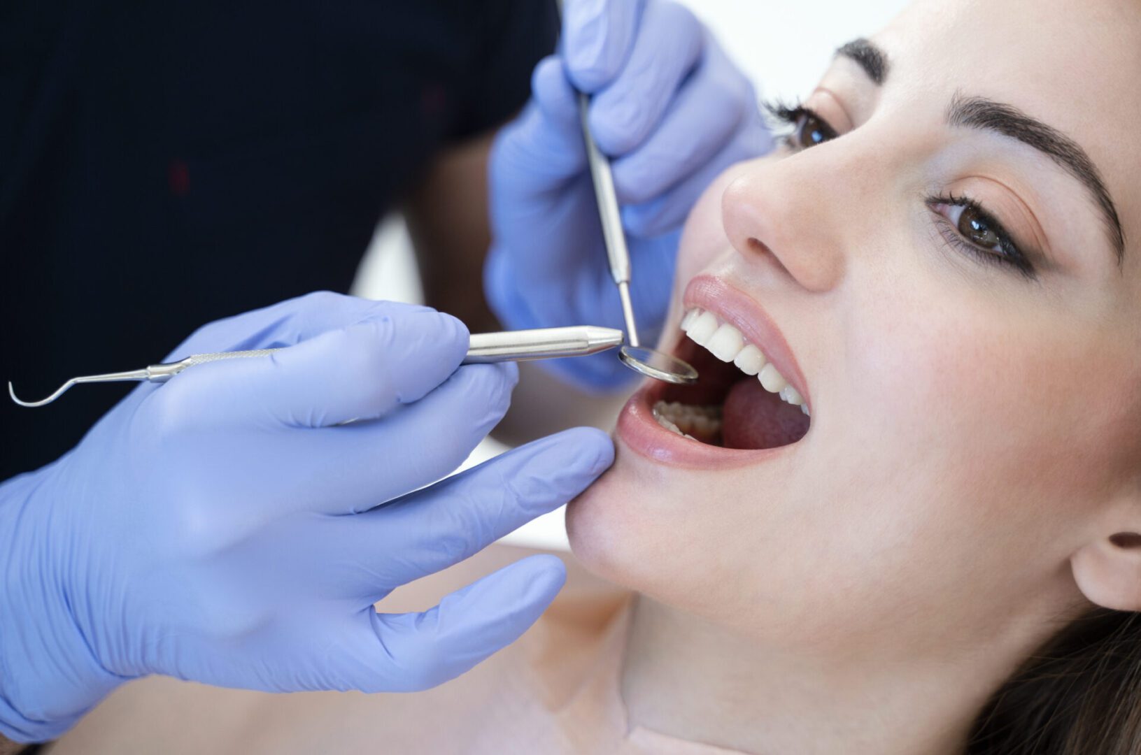 Close up portrait of a smiling pretty woman is receiving dental checkup