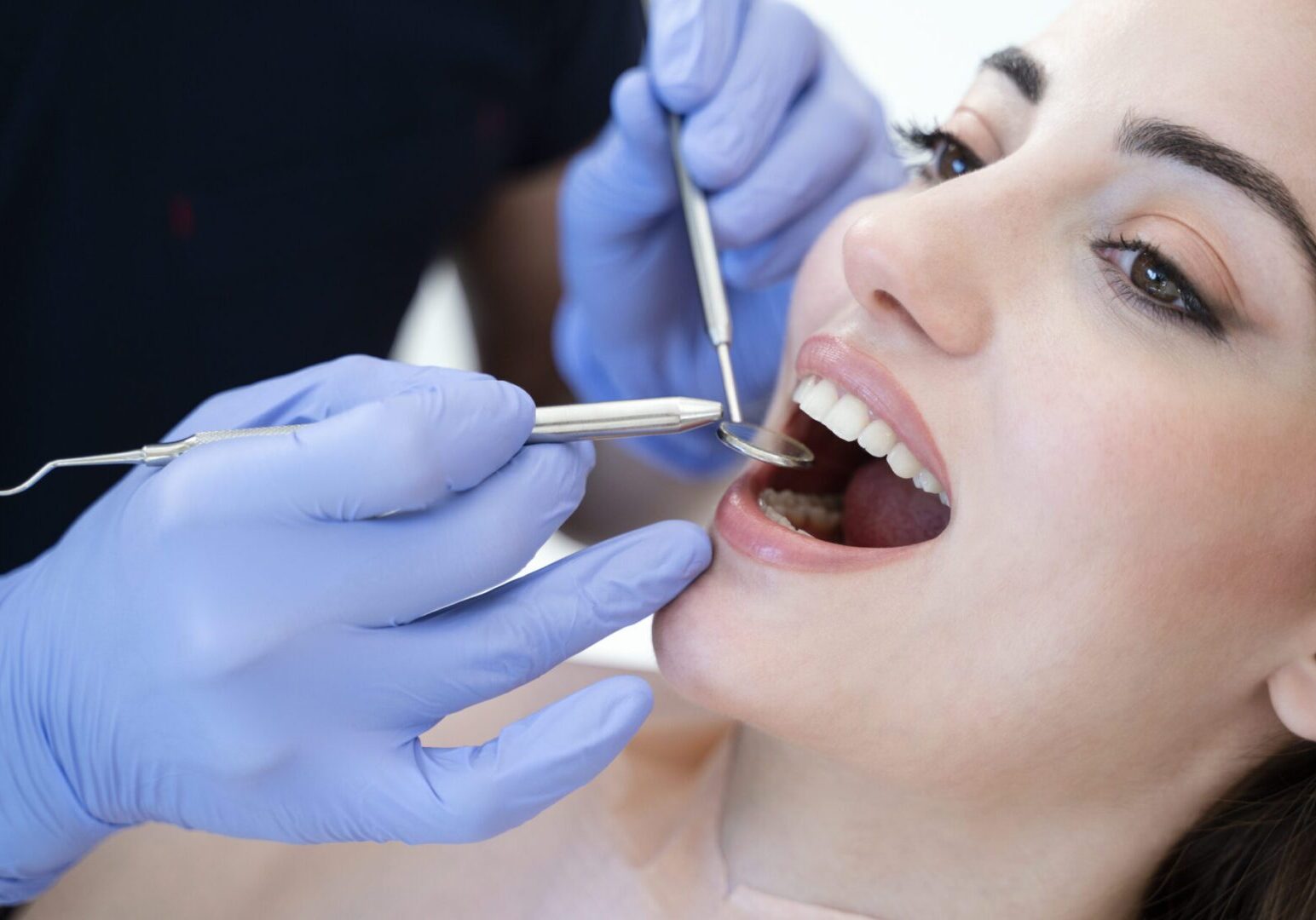 Close up portrait of a smiling pretty woman is receiving dental checkup